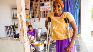 A woman aided by crutches walks through a kitchen