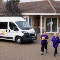 Exterior view of bungalow red bricked building with a Leonard Cheshire branded minibus parked in the forecourt